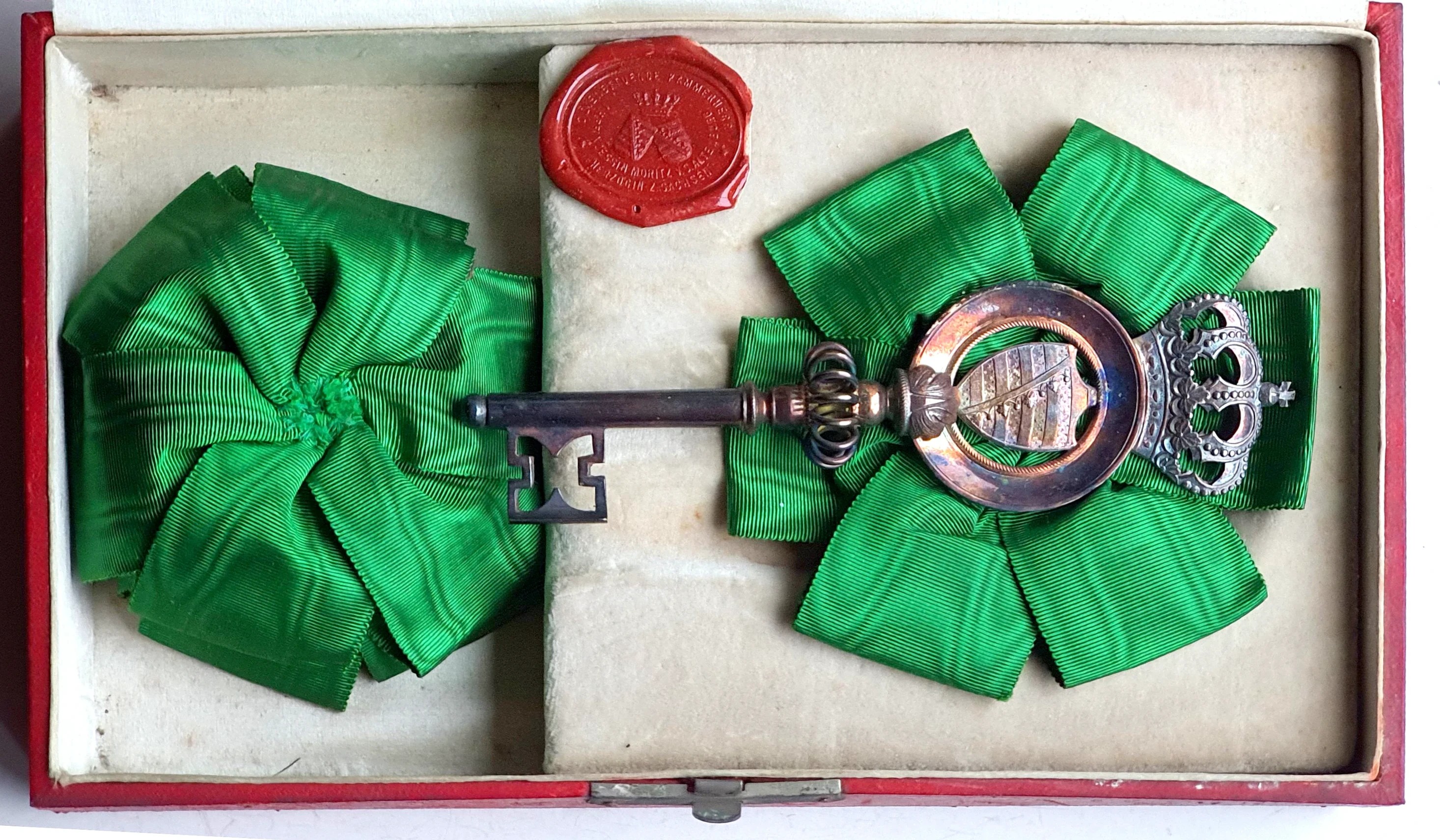 Ein geöffnetes Etui mit einem Kammerherrenschlüssel aus der Regierungszeit Herzog Ernsts I. von Sachsen-Altenburg (1853–1908) mit Ersatzschleife.